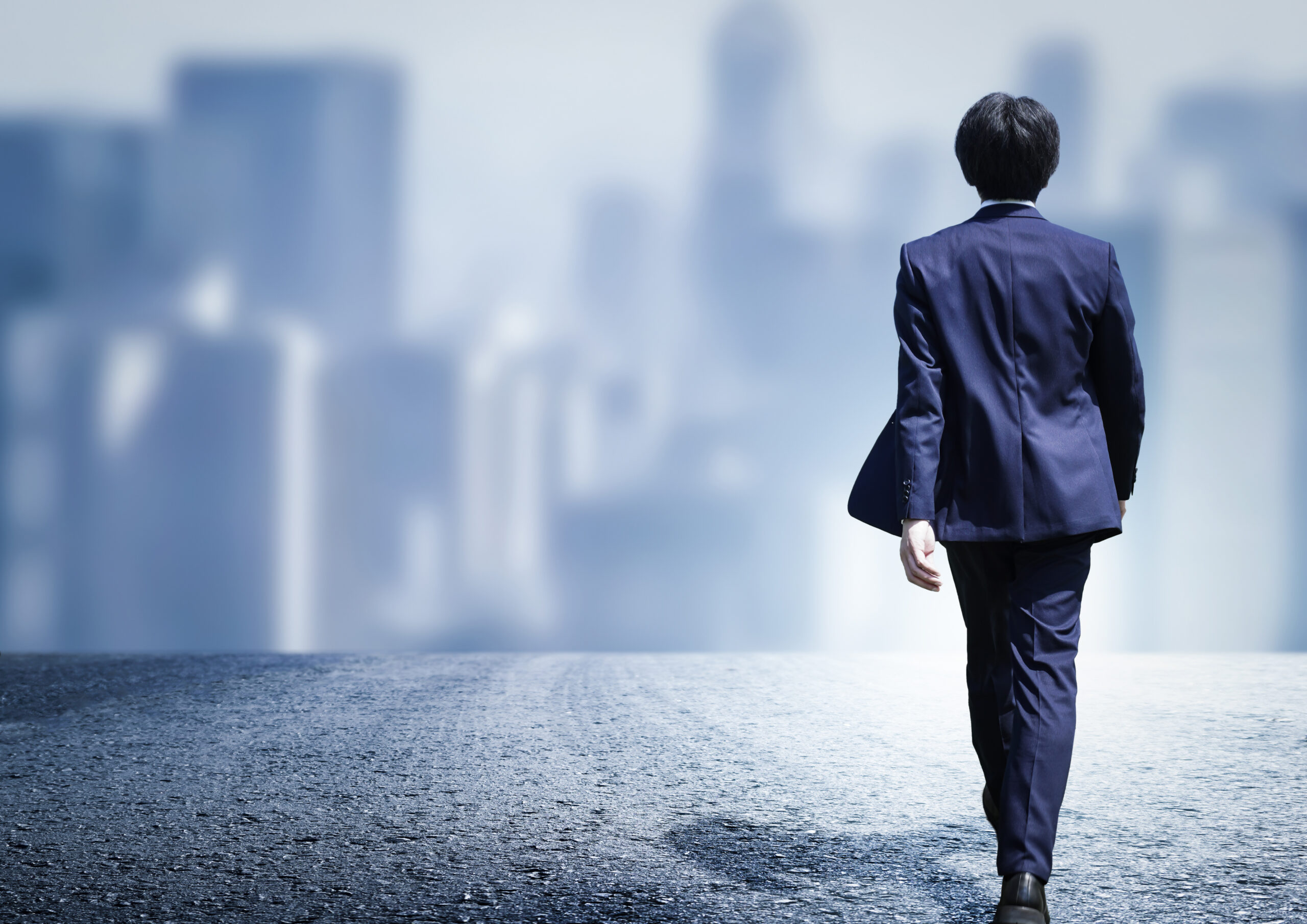 都市の街並みを歩くスーツの男性